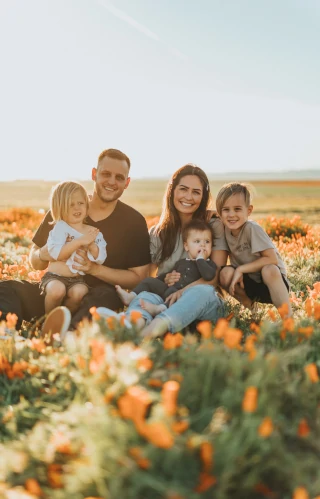 Glückliche Familie mit Vater, Mutter und drei Kindern in einem Blumenfeld