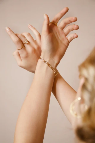 Frau hält ihre Arme überkreuzt, um zwei Ringe und ein Armband zu präsentieren